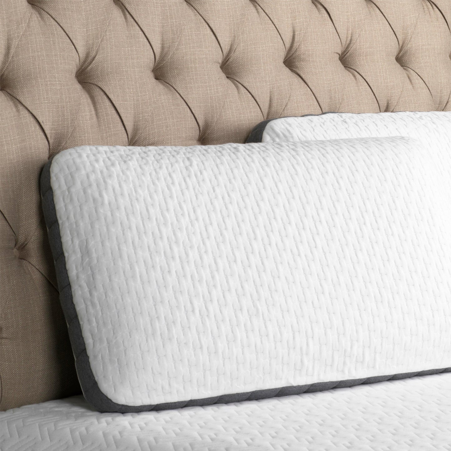 Two-Sided-bamboo-charcoal-Pillow with cool gel slab on one side, and plain charcoal infused memory foam on the other side. Pillow with white and gray cover leans on an upholstered headboard