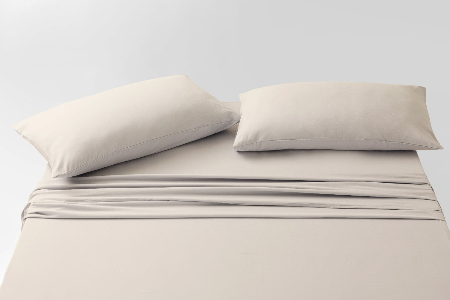 Beige bed sheets and pillows on a white background