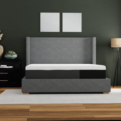 Gray upholstered bed with white mattress in a room with dark walls and wooden flooring.