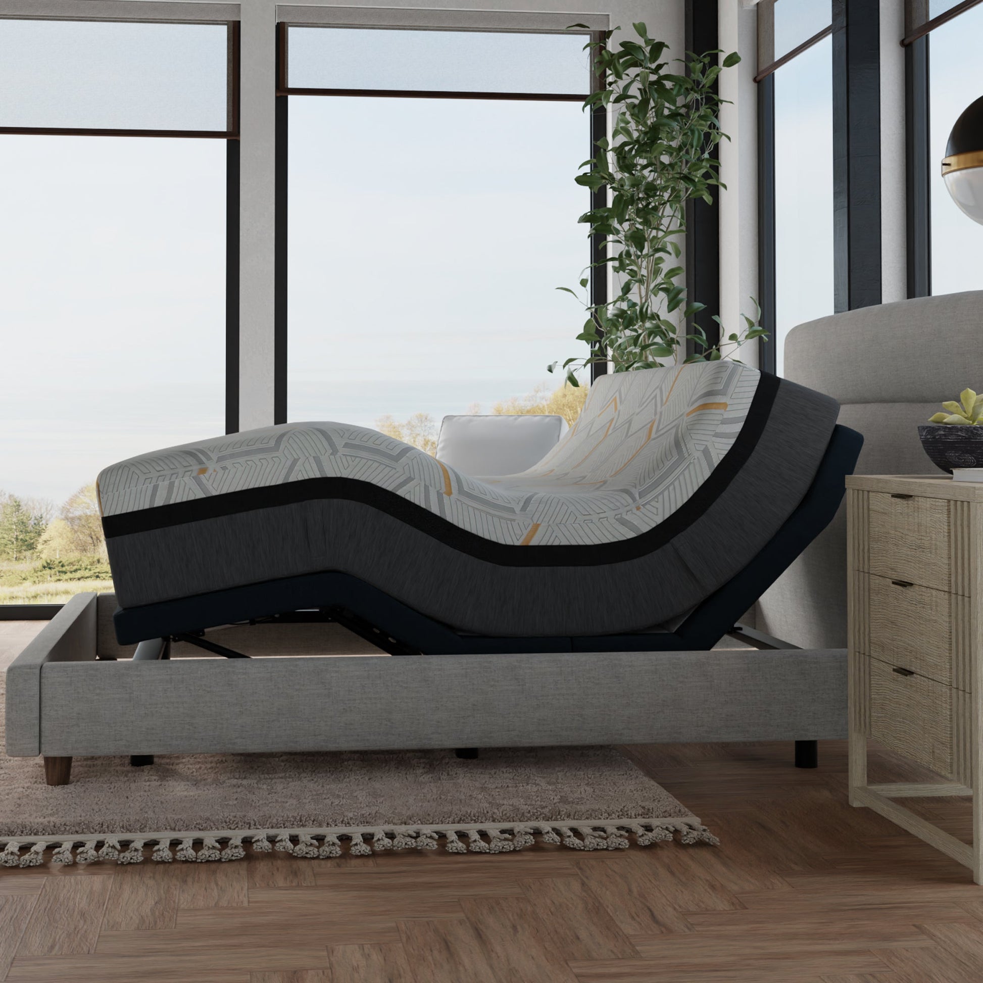 Gray adjustable bed in a room with large windows and a plant. 14 inch hybrid copper queen mattress on adjustable bed base