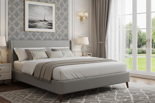 Neatly made upholstered platform bed in a stylish bedroom with patterned wallpaper and large windows. King size Bed / mattress. White sheets