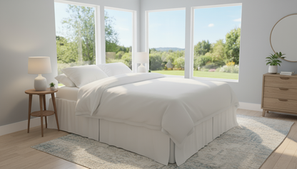 Steel Folding base with mattress and bedding in a well lit room with large windows. There is a bedskirt added  to show that the space can be covered for hidden storage