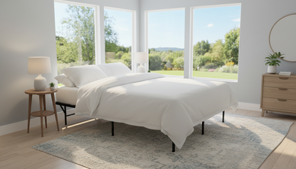 Steel Folding base with mattress and bedding in a well lit room with large windows. No bedskirt to show available space underneath at 13" clearance