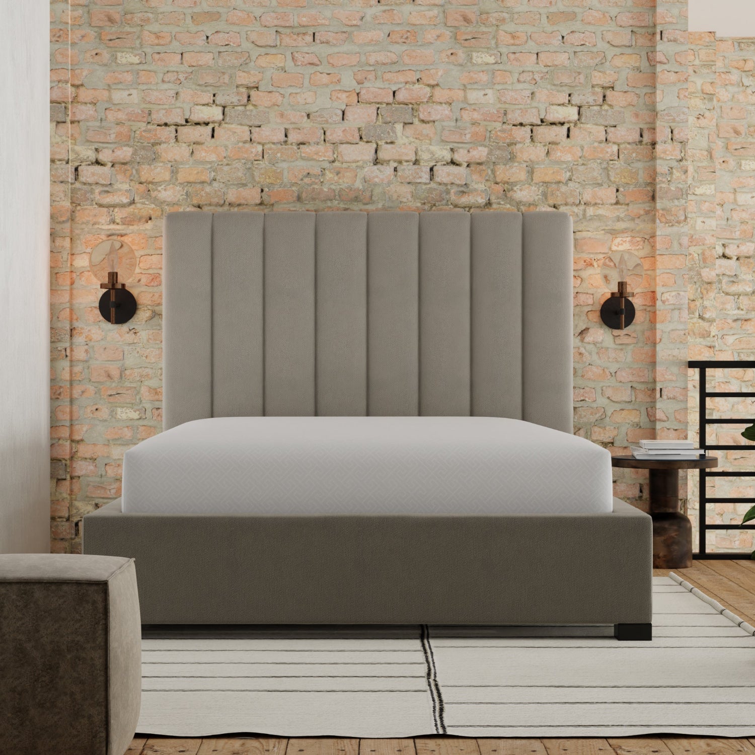Gray upholstered bed against a brick wall with a side table and lamp. mattress is covered with a mattress protector called Fresh. Queen size