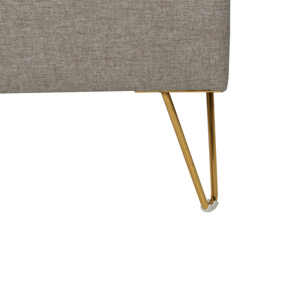 Close-up of a gray upholstered bed with brass metal legs on a white background