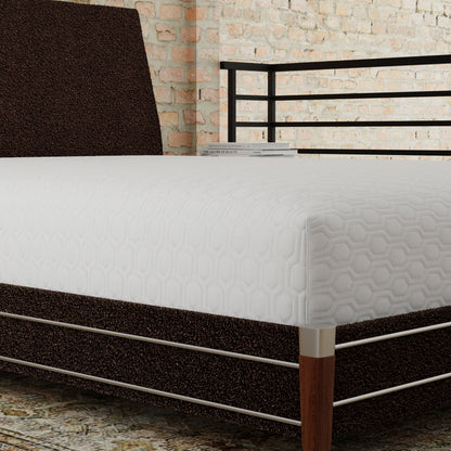 Bed with a white mattress and a dark brown headboard against a stone wall. Mattress is covered with the ICE mattress protector- textured surface and an elongated hexagon pattern