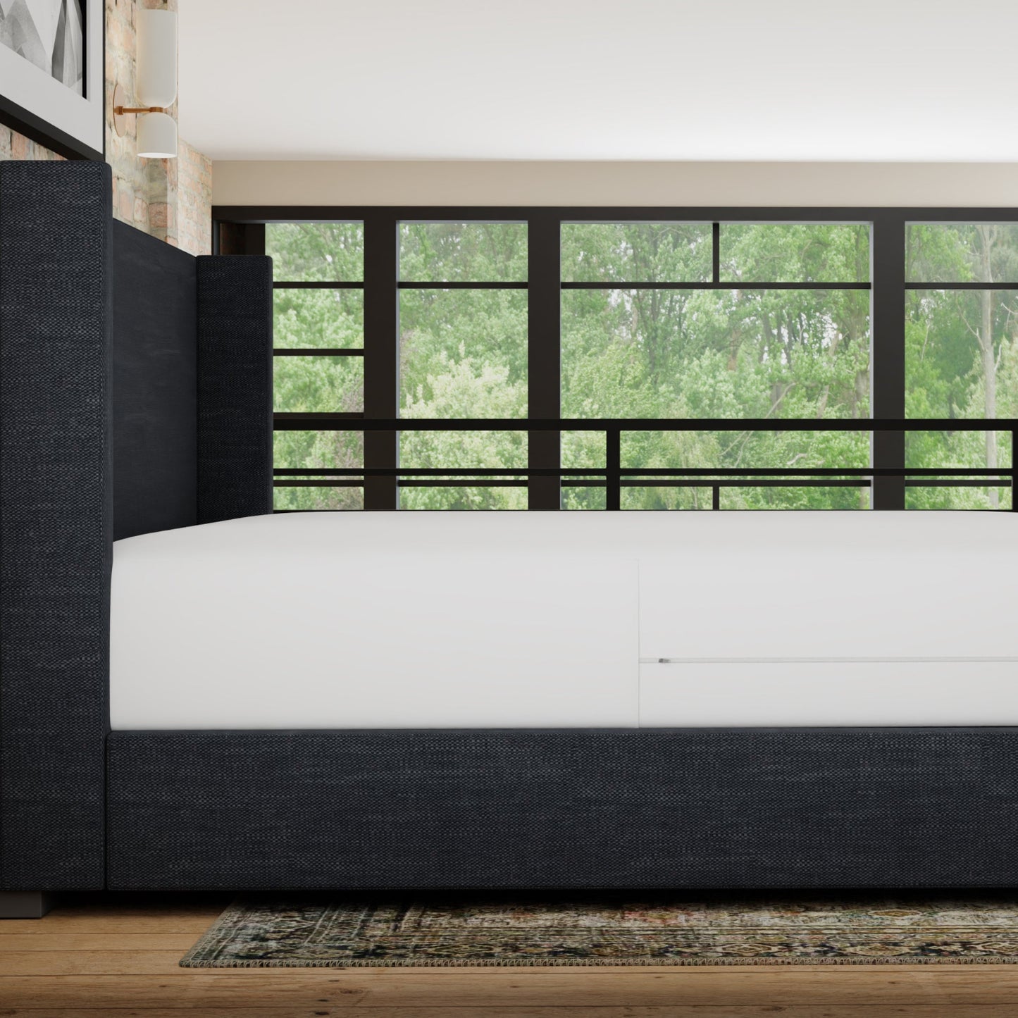 Modern bedroom with a bed and large window showing greenery outside. mattress has a waterproof mattress encasement on it- side view
