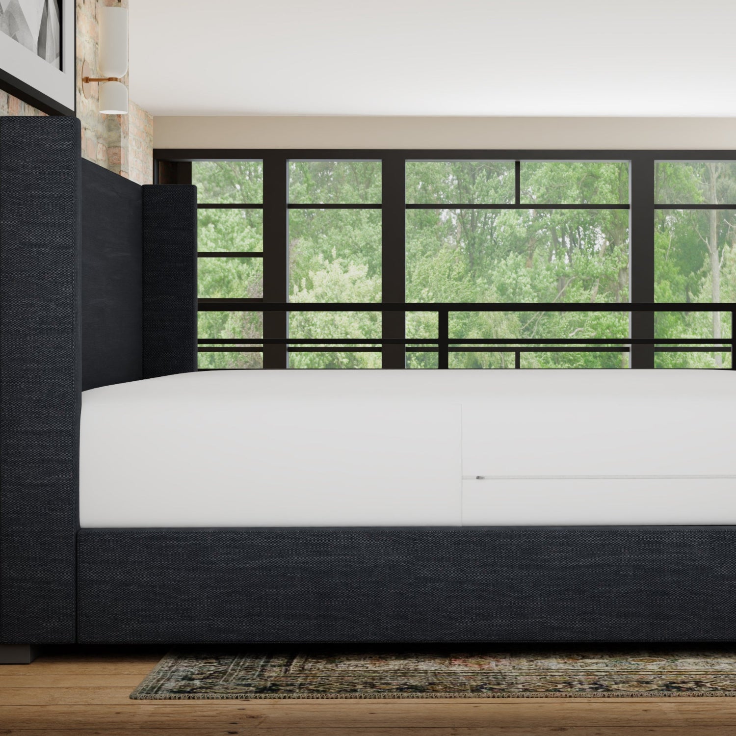 Modern bedroom with a bed and large window showing greenery outside. mattress has a waterproof mattress encasement on it- side view
