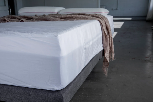 Bed with white mattress cover and brown blanket in a minimalistic room. Premium mattress Encasement-Protector_on queen size mattress
