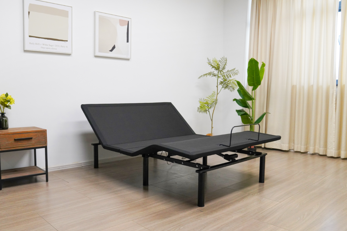 Black adjustable bed in a room with a wooden floor, white walls, and decorative plants. RIO_2.0_adjustable bed base in zero gravity position- queen size