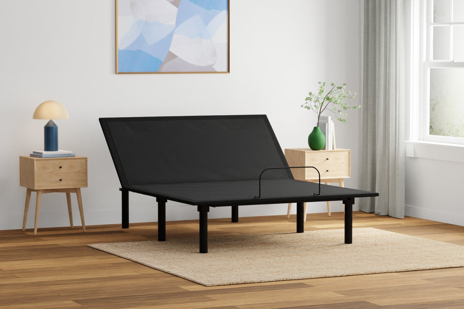 Black adjustable bed in a room with wooden flooring and a painting on the wall. Rio1.0 adjustable bed base. head elevated