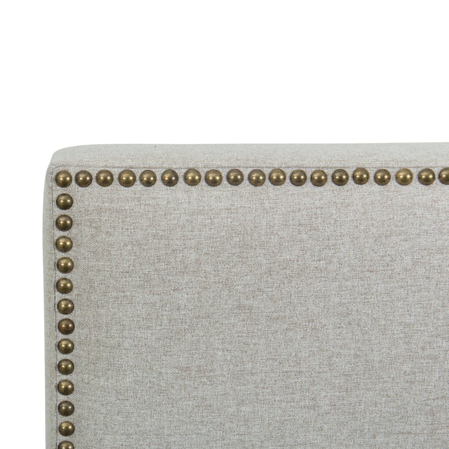 Close-up of a light gray upholstered bed with brass nailhead trim on a white background