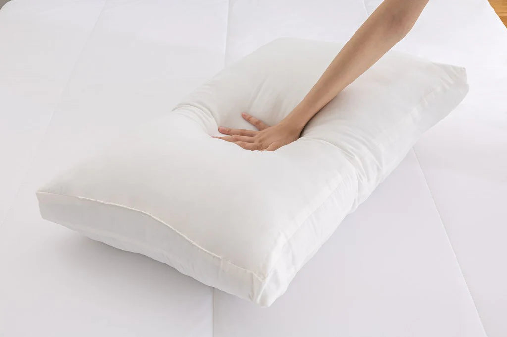 Hand pressing into a soft washed down alternative pillow to demonstrate plush cushioning and adaptive support.
