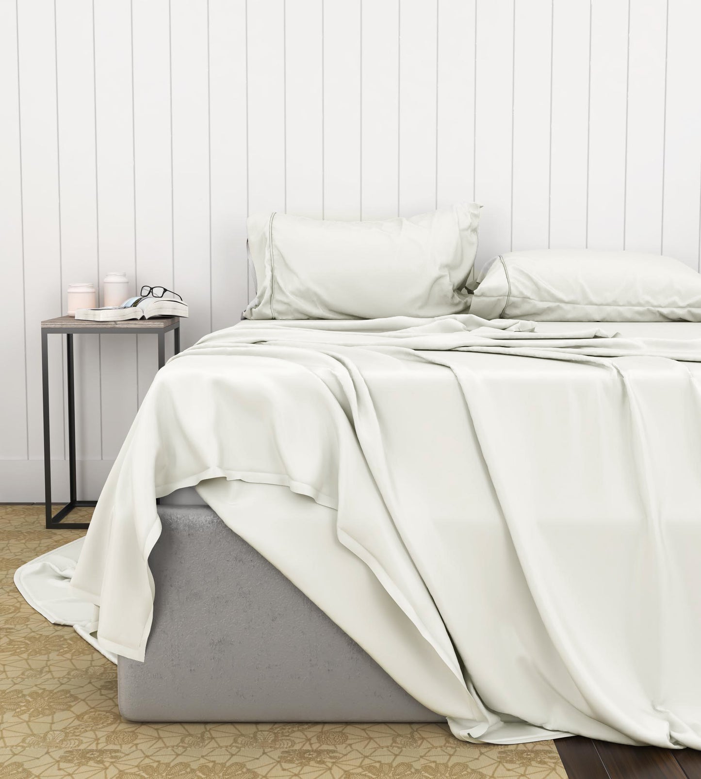 Neatly made bed with ivory sheet set on a bed in a room with a wooden floor and white paneled walls.