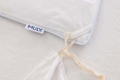 Close-up of a white cooling duvet insert with a visible Mlily brand tag, tied with a cream-colored string on a matching white duvet surface.